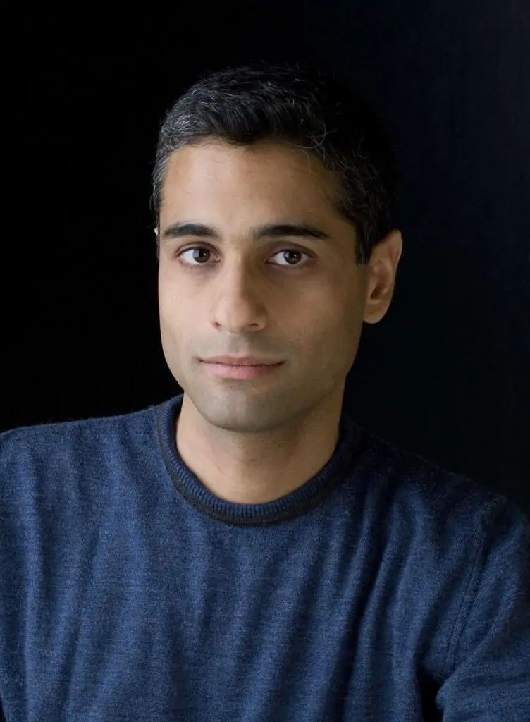 Head-and-shoulders portrait of Siddharth Kara in a blue sweater against a dark background