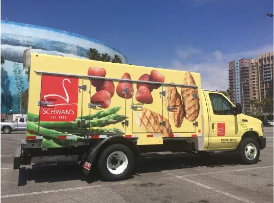 Yellow Schwan’s delivery truck with frozen food graphics parked in a city lot